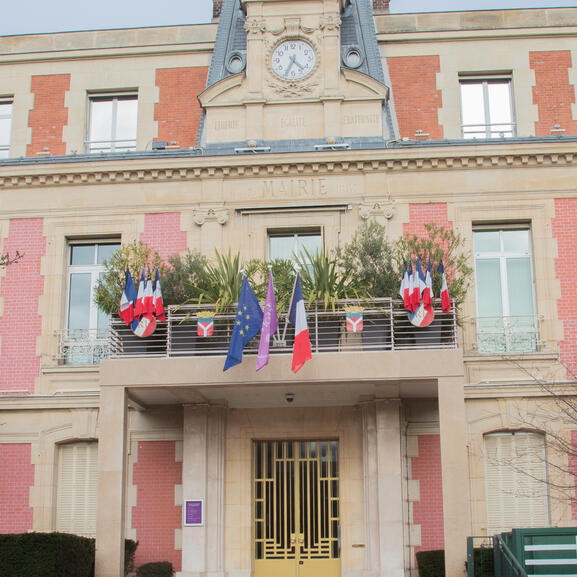 Photo des drapeaux français, européen et alfortvillais accrochés sur la façade de l'Hôtel de Ville.