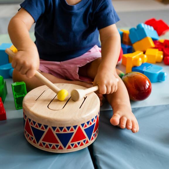 Photo d'illustration - Eveil musical Photo d'illustration : éveil musical en crèche, avec un jeune enfant jouant du tambour en bois.